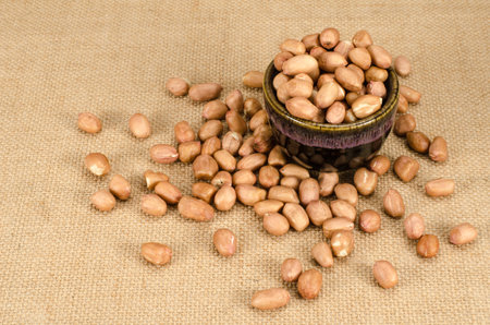 Image of raw peanuts in ceramic bowl  on brown sack background