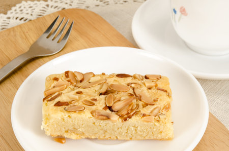 Image of brown square cake in white ceramic dish on brown sack background