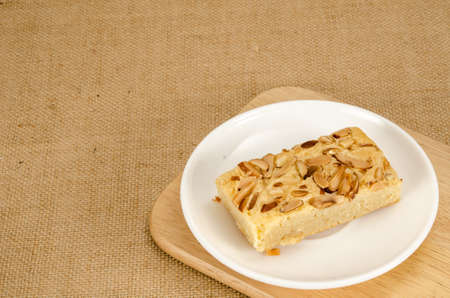 Image of brown square cake in white ceramic dish on brown sack backgroundの写真素材