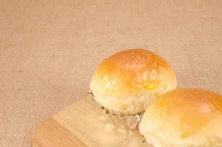 Bread buns on wooden block on brown sack background