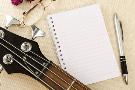 Blank paper with pen on electric bass guitar on brown sack backgroundの写真素材