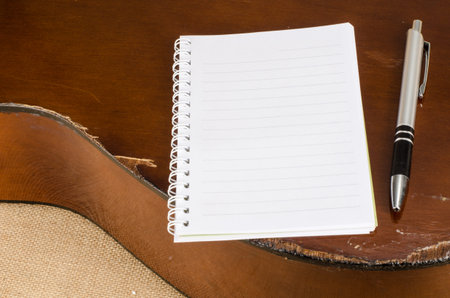 Image of white blank paper with pen on old acoustic guitar on brown sack backgroundの写真素材