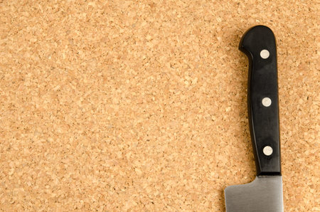 Black handle knife on cork background