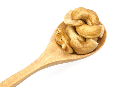 Cashew nuts in wooden spoon on white backgroundの写真素材