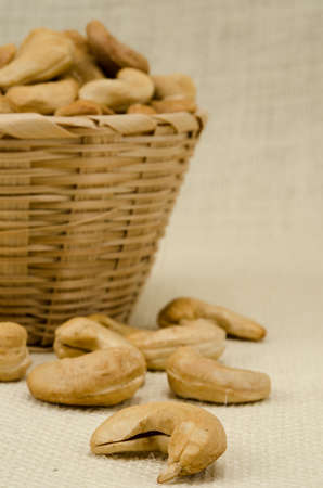 Cashew nuts in bamboo woven on sack backgroundの写真素材