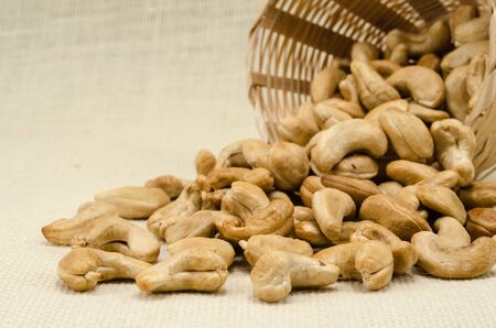 Cashew nuts in bamboo woven on sack backgroundの写真素材