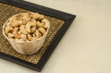Cashew nuts in bamboo woven on sack backgroundの写真素材