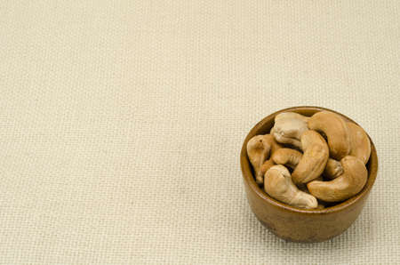 Cashew nuts in ceramic bowl on sack backgroundの写真素材