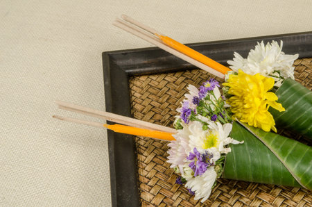 Image of flowers in banana leaf cone with incense and candle on sack fabric backgroundの写真素材