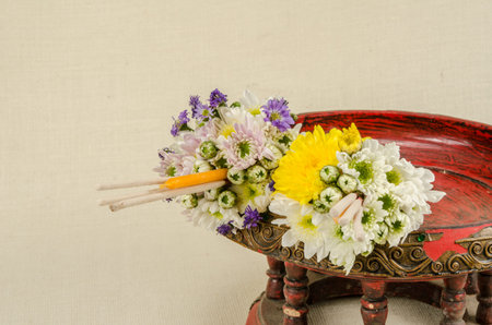 Image of flowers in banana leaf cone with incense and candle on sack fabric background