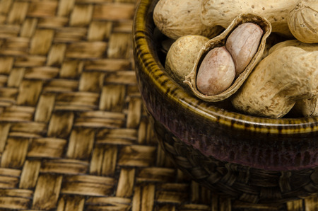 Image of peanuts in ceramic bowl on bamboo wovenの写真素材