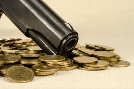 Gun and Thai baht coins on brown sack backgroundの写真素材