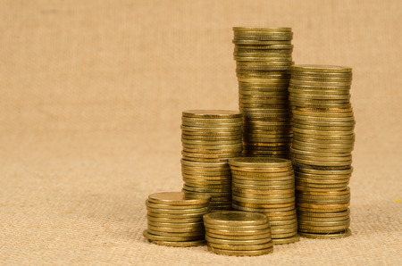 Stack of gold coins on brown sack backgroundの写真素材