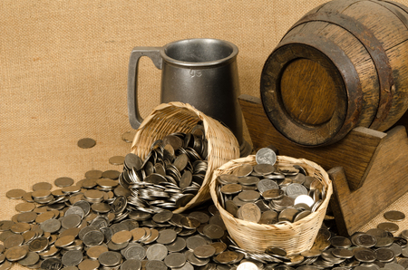 Stack of coins with wooden barrel on brown sack backgroundの写真素材