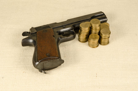 Gun and Thai baht coins on brown sack background