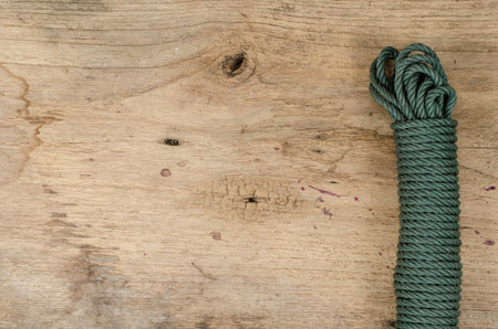 Coiled green nylon rope on old woodの写真素材