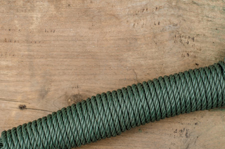 Coiled green nylon rope on old wood
