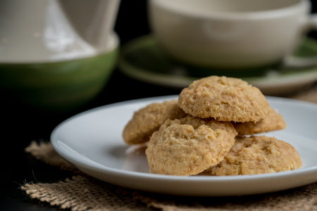 Brown butter cookie in white ceramic plate and brown sack on black background