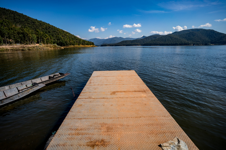 Rusty metal small harbor on the lake with mountain and blue sky backgroundの写真素材