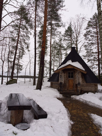 Log lake hut in the woods during winter with snow and ice footpathの写真素材