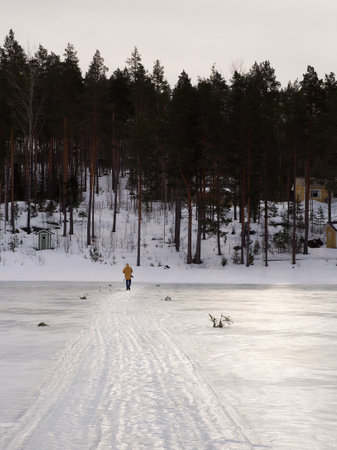 Man walking on a frozen lake path with trees in the backの写真素材