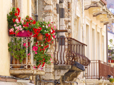 Building facades and balconies in Taormina streets full of bougainvillea flowers in a sunny summer day, Sicily, Italyの写真素材