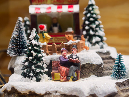 Miniature Christmas scene with a couple sitting on a bench with snow and Christmas trees aroundの写真素材
