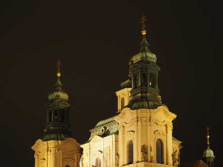 Ornate church towers with golden spires and domes lit up against dark night sky. Prague, Czech Republicの写真素材