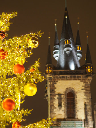 Illuminated Christmas tree with ornaments in foreground, gothic church tower lit up at night. Church of Our Lady, Pragueの写真素材