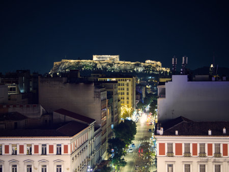 Nighttime cityscape of Athens with illuminated Acropolis atop hill, overlooking urban Athena street. Athens, Greeceの写真素材