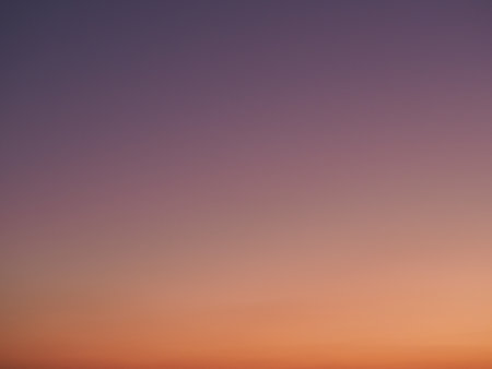 Smooth gradient of purple and orange hues in a clear twilight skyの写真素材