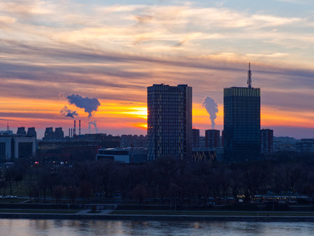 Belgrade urban skyline at dusk with tall buildings and smoke stacks against a colorful skyの写真素材