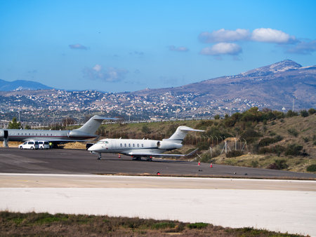Two private jets on an airport runway with a scenic view of a mountainous landscape behind themの写真素材