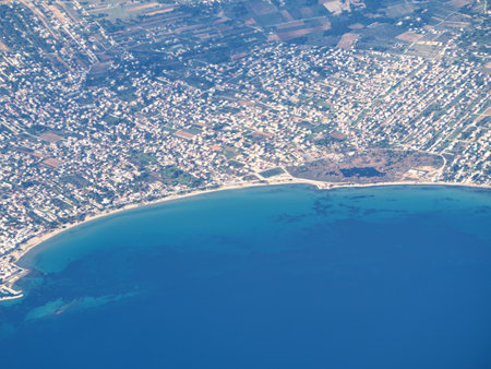 Aerial photograph showing a densely populated coastal city of Artemida with a curved shoreline and blue seaの写真素材
