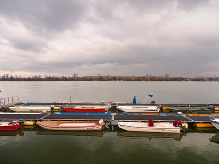 Small boats of various colors moored at a Danube river dock under an overcast sky. Zemun, Belgradeの写真素材