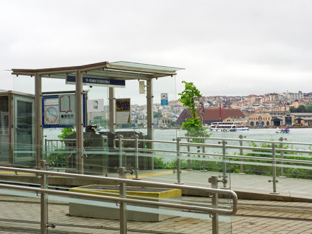Modern tram shelter on waterfront platform with view of city skyline and harbor in background. Instabul, Turkeyの写真素材