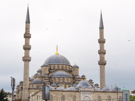 Majestic Ottoman-style mosque with a large central dome and two tall minarets against a cloudy skyの写真素材