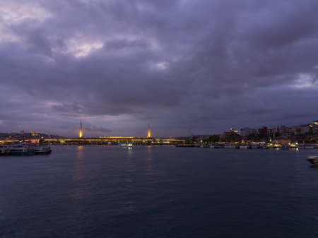 Illuminated bridge over Bosphorus with moody sky and city lights in Istanbul at duskの写真素材
