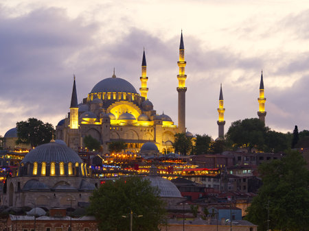 Suleymaniye Mosque glowing at twilight, surrounded by minarets and city lights in Istanbul, Turkeyの写真素材