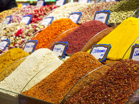 Various vibrant spices displayed in mounds at a market, with labeled price tags visibleの写真素材
