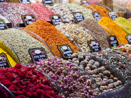 Various colorful spices and dried flowers in bins at a market stall with labelsの写真素材