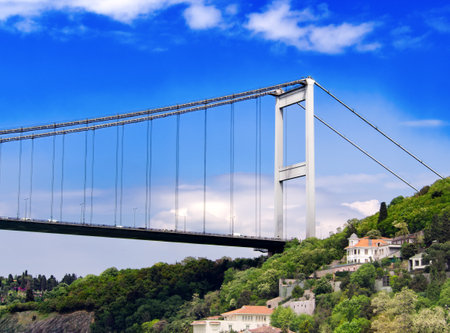 15 July Martyrs bridge with houses and greenery on hillside beneath blue skyの写真素材