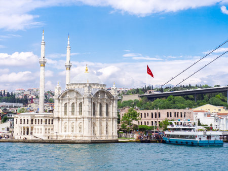 Ornate Ortakoy Mosque with minarets on Bosphorus strait, Istanbul cityscape with bridge and boatsの写真素材