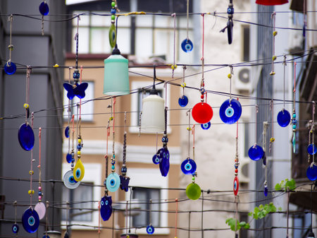 A display of various colorful glass and ceramic ornaments, including evil eye charms, hanging on stringsの写真素材