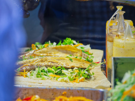 Closeup of a sandwich being prepared with fresh vegetables and meat on a wooden cutting boardの写真素材