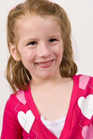 Young girl in a heart sweater making funny faceの写真素材
