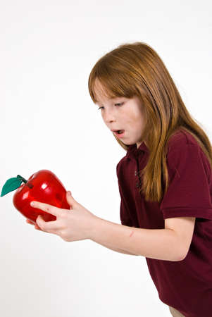 Female school child holding a clear plastic red appleの写真素材