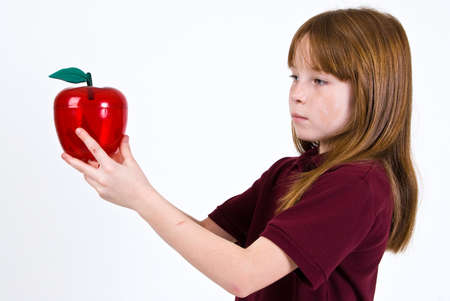 Female school child holding a clear plastic red appleの写真素材