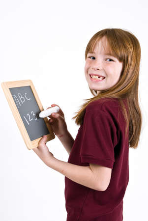 Young school girl writing on chalk boardの写真素材