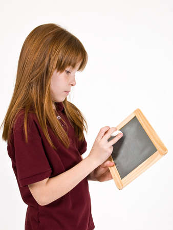 Young school girl writing on chalk boardの写真素材